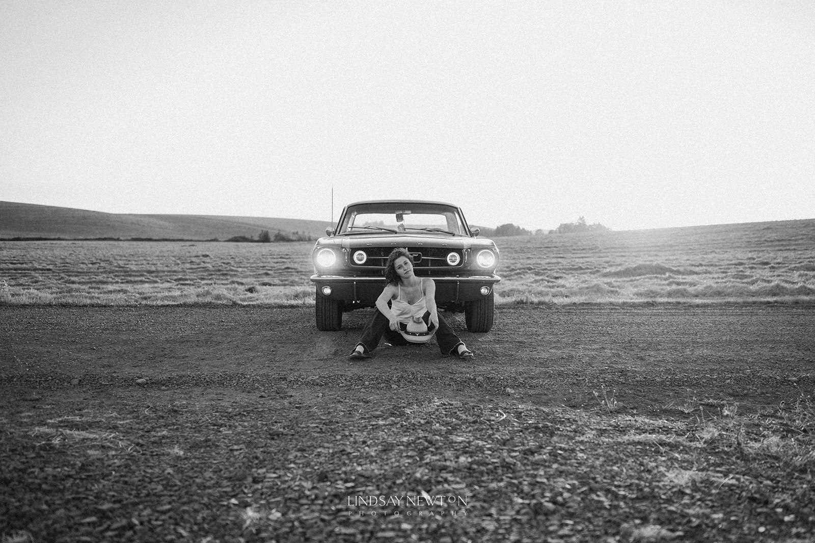 senior photo of a girl sitting in front of a mustang