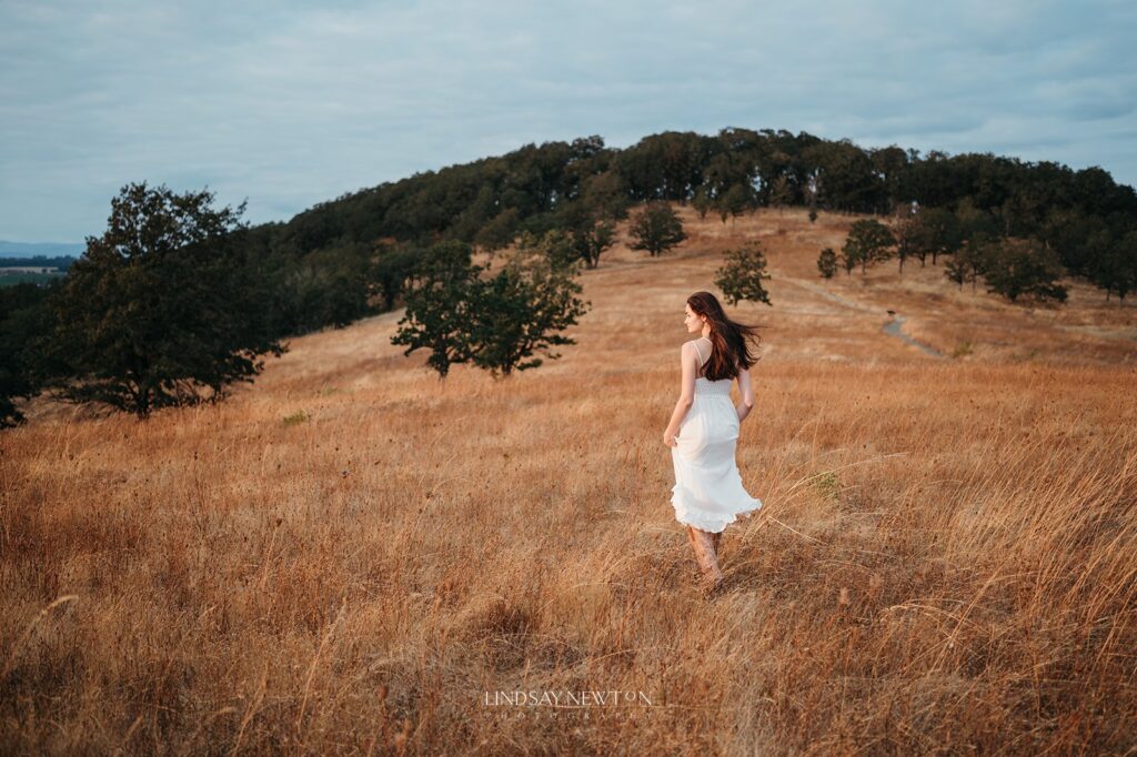 senior girl walking through a field for her senior photography experience