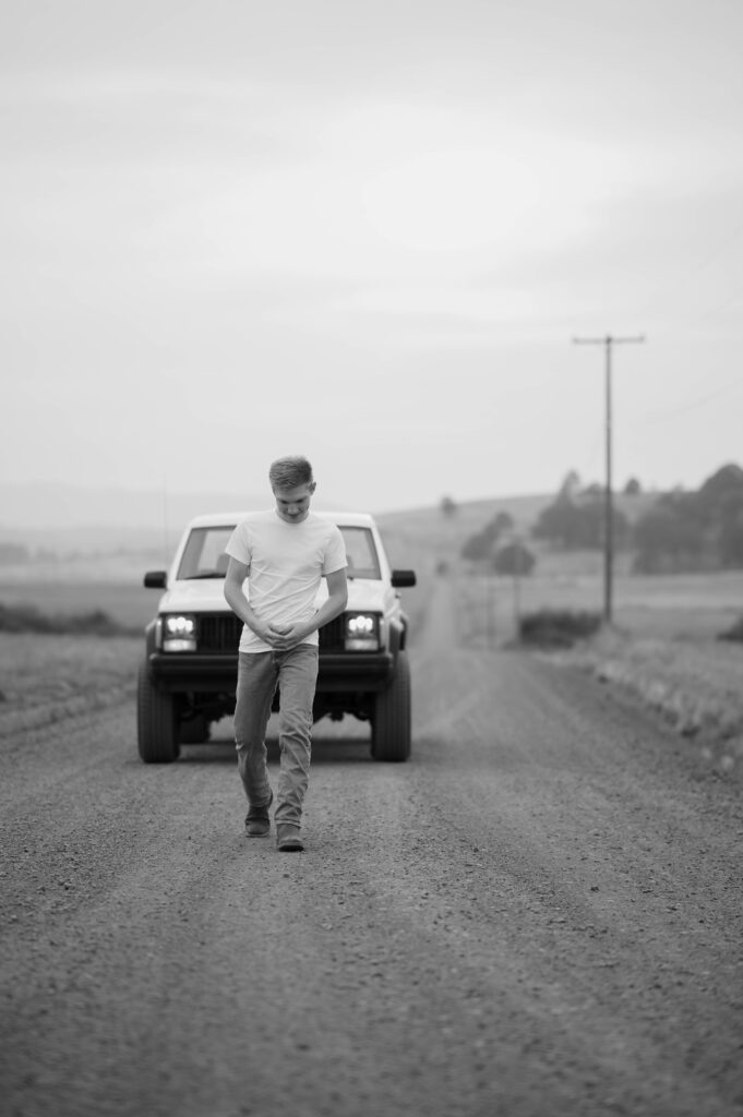 high school senior guy walking on gravel road 