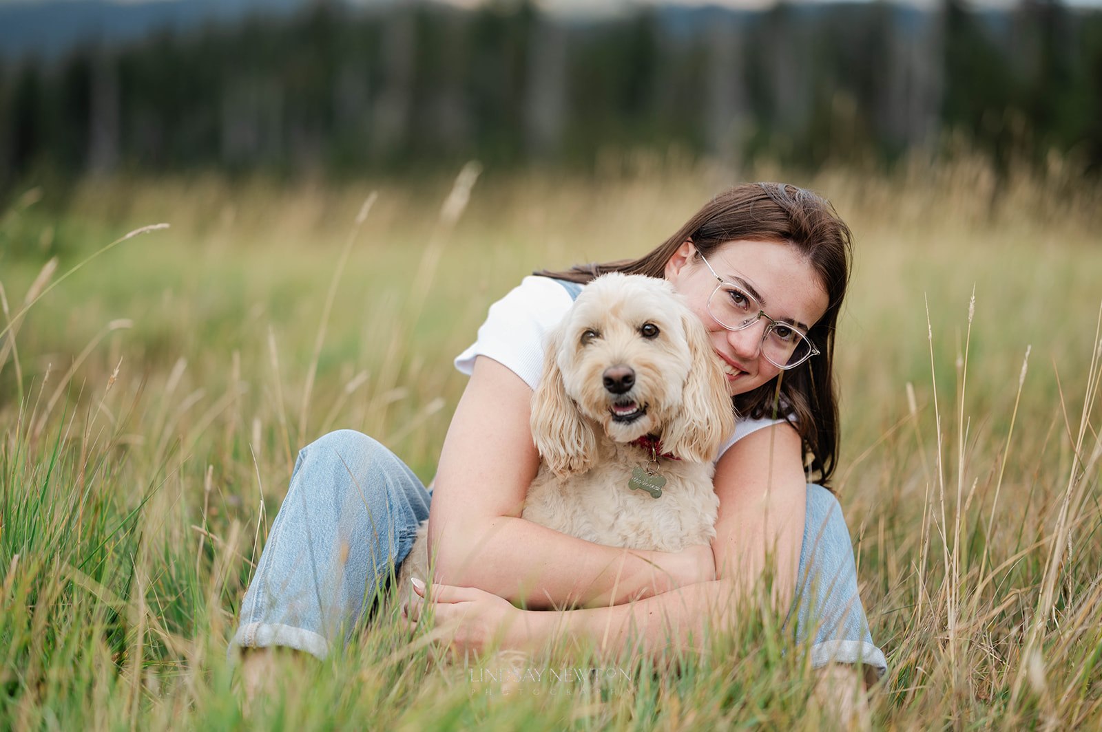 senior girl sitting in a field with her dog