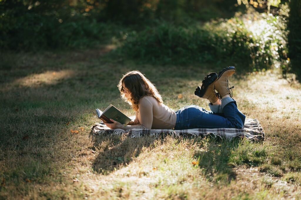 Fall senior session at Silver Falls State Park. Senior Girl reading a book in the sun.