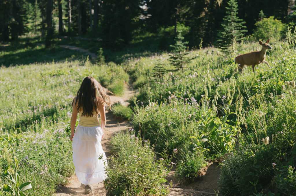 Magical senior portrait moment as a deer walks along the trail during a Tipsoo Peak wildflower session.