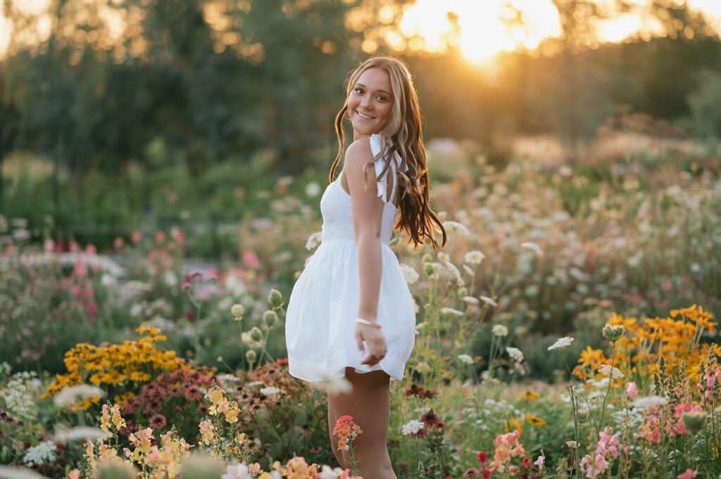 Oregon senior photos among summer flowers with soft golden morning light